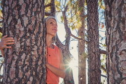Frau umarmt eine Pinie auf Teneriffa, sonnen scheint durch Bäume