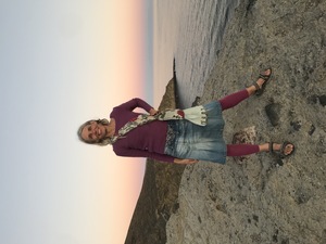 Barbara steht auf Felsen am Meer nach Sonnenuntergang in der Abendröte