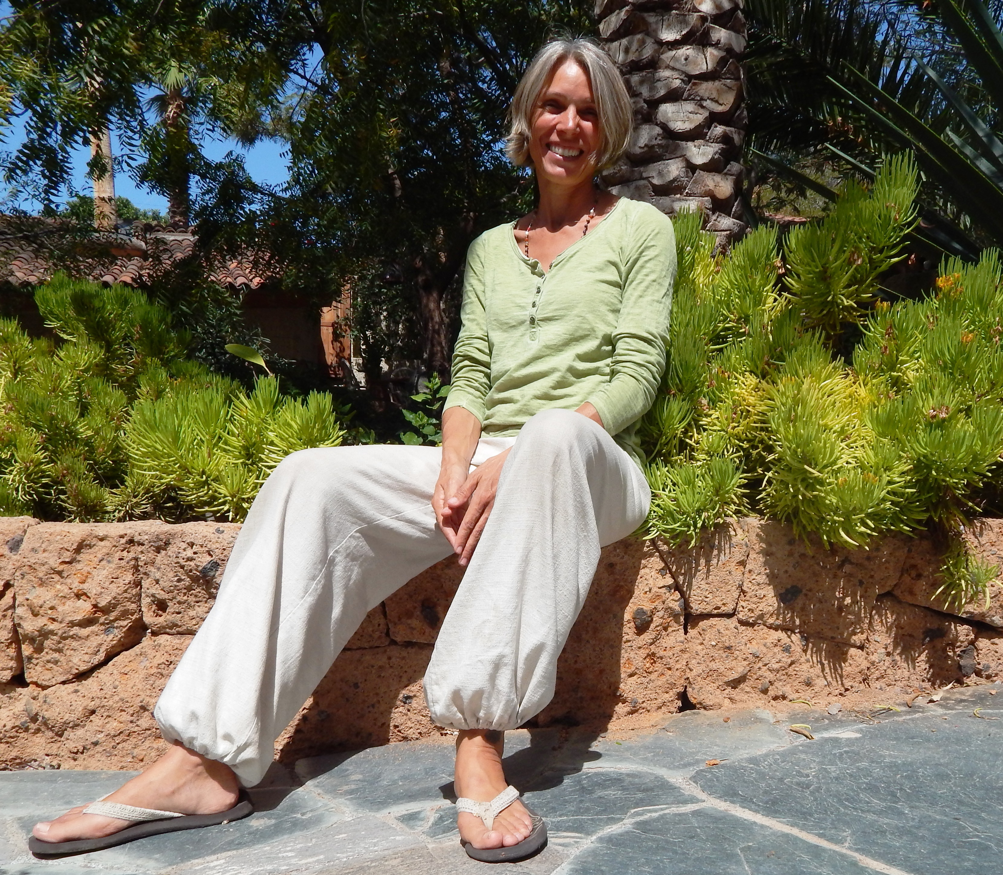 Barbara Stumpp sitzt in einem schönen Garten und lächelt