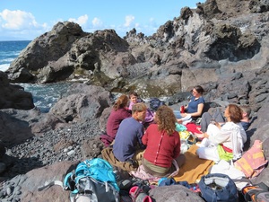 Gruppe von Menschen sitzt am Meer von teneriffa zusammen auf dem Boden
